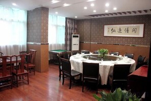 A dining area with a pool table, round tables, and chairs.