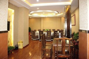 Un comedor de hotel con varias mesas y sillas, piso de madera y un diseño moderno en el techo.