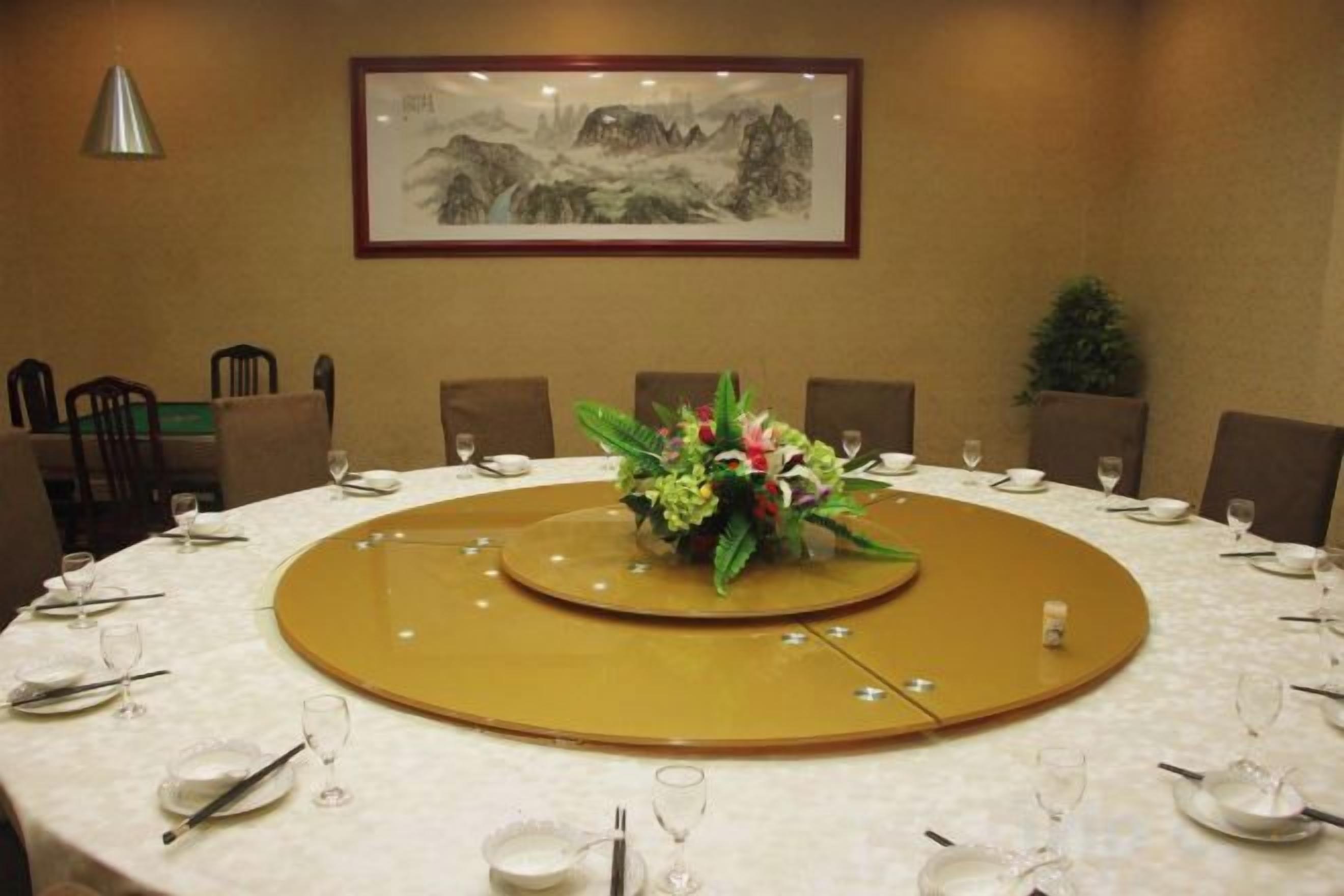 A conference room with a round table, chairs, and a framed artwork on the wall.