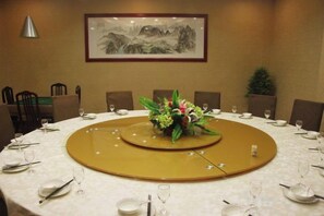Un salón de conferencias con una mesa redonda, sillas y una obra de arte enmarcada en la pared.