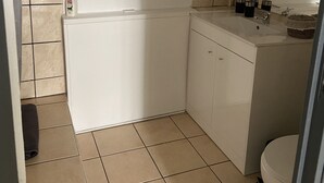 Een kleine, schone badkamer met toilet, wastafel en een zeepdispenser aan de muur.