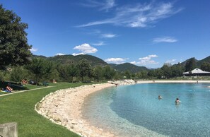 A clear blue pool surrounded by a grassy area with people sunbathing and swimming. - Studio in the center of Digne les bains (Digne les bains)
