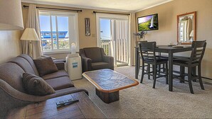 A hotel room with a balcony, a sofa, a coffee table, a TV, and a dining area with chairs. - ML 232: Your appealing summer oasis with lift views! Next to bike trails! (Snowshoe)