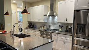 A modern kitchen with white cabinets, stainless steel appliances, and pendant lighting. - Coastal Farmhouse-located in "The Best Coastal Small Town in America" -USA Today (Saugatuck)