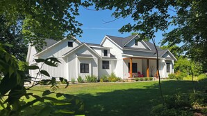 A two-story house with a covered porch and a well-maintained lawn. - Coastal Farmhouse-located in "The Best Coastal Small Town in America" -USA Today (Saugatuck)