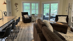 A modern kitchen with a bar area, a black leather chair, a brown sofa, and a dining table with chairs. - Coastal Farmhouse-located in "The Best Coastal Small Town in America" -USA Today (Saugatuck)
