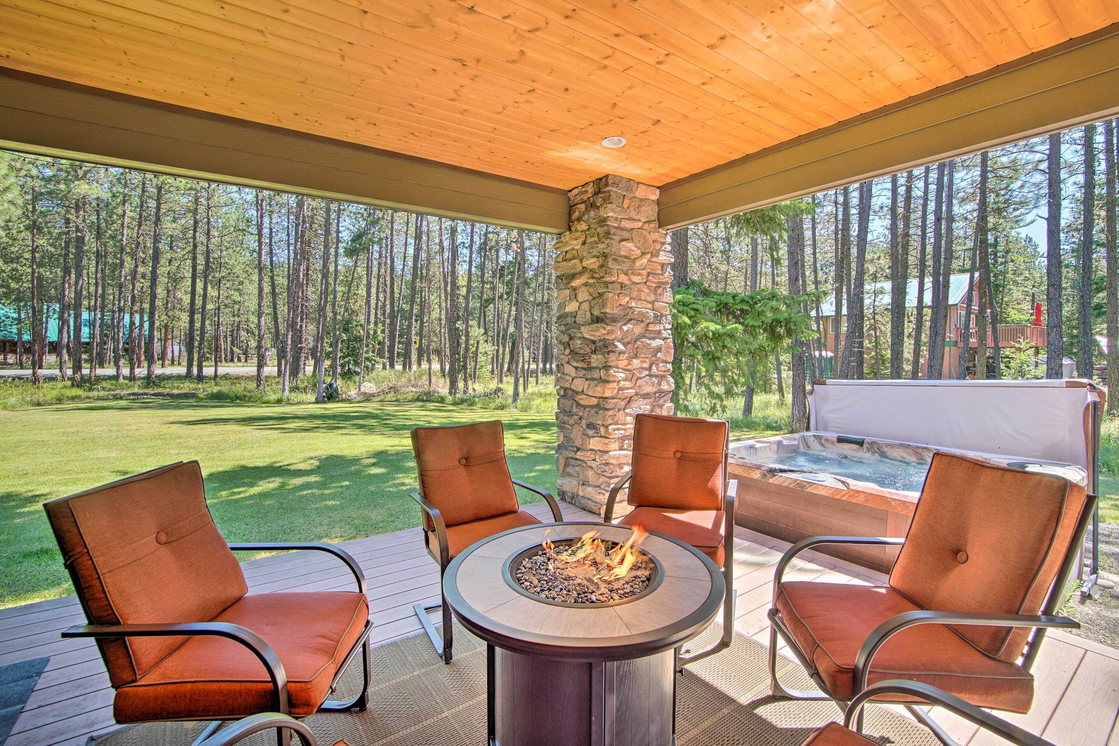 A deck with a stone pillar, a fire pit, and two chairs.