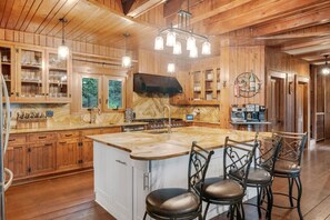 A spacious kitchen with wooden cabinets, a large island with bar stools, and a built-in microwave.