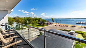 En balkon med udsigt over en lystbådehavn, en vej og et grønt område med træer.