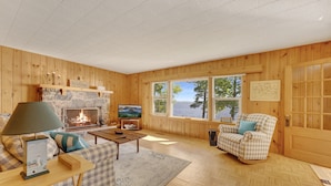 A cozy living room with a fireplace, a television, and a view of the outdoors.