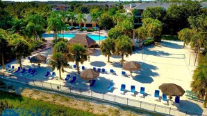 A resort with a pool area, sun loungers, and thatched umbrellas. - Hidden Oasis 20 minutes from Disney and Universal (Davenport)