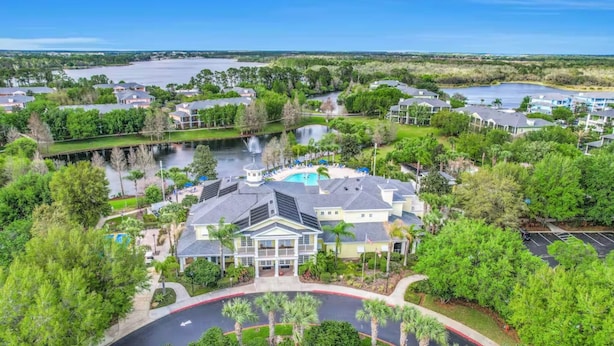A resort with a central pool, surrounded by lush greenery and a view of a lake. - Hidden Oasis 20 minutes from Disney and Universal (Davenport)