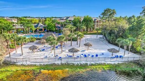 A resort with a pool area, lounge chairs, and palm trees. - Hidden Oasis 20 minutes from Disney and Universal (Davenport)