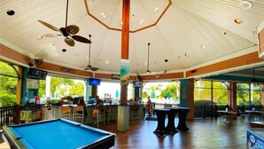 A pool table in a spacious room with ceiling fans, a bar area, and large windows. - Hidden Oasis 20 minutes from Disney and Universal (Davenport)