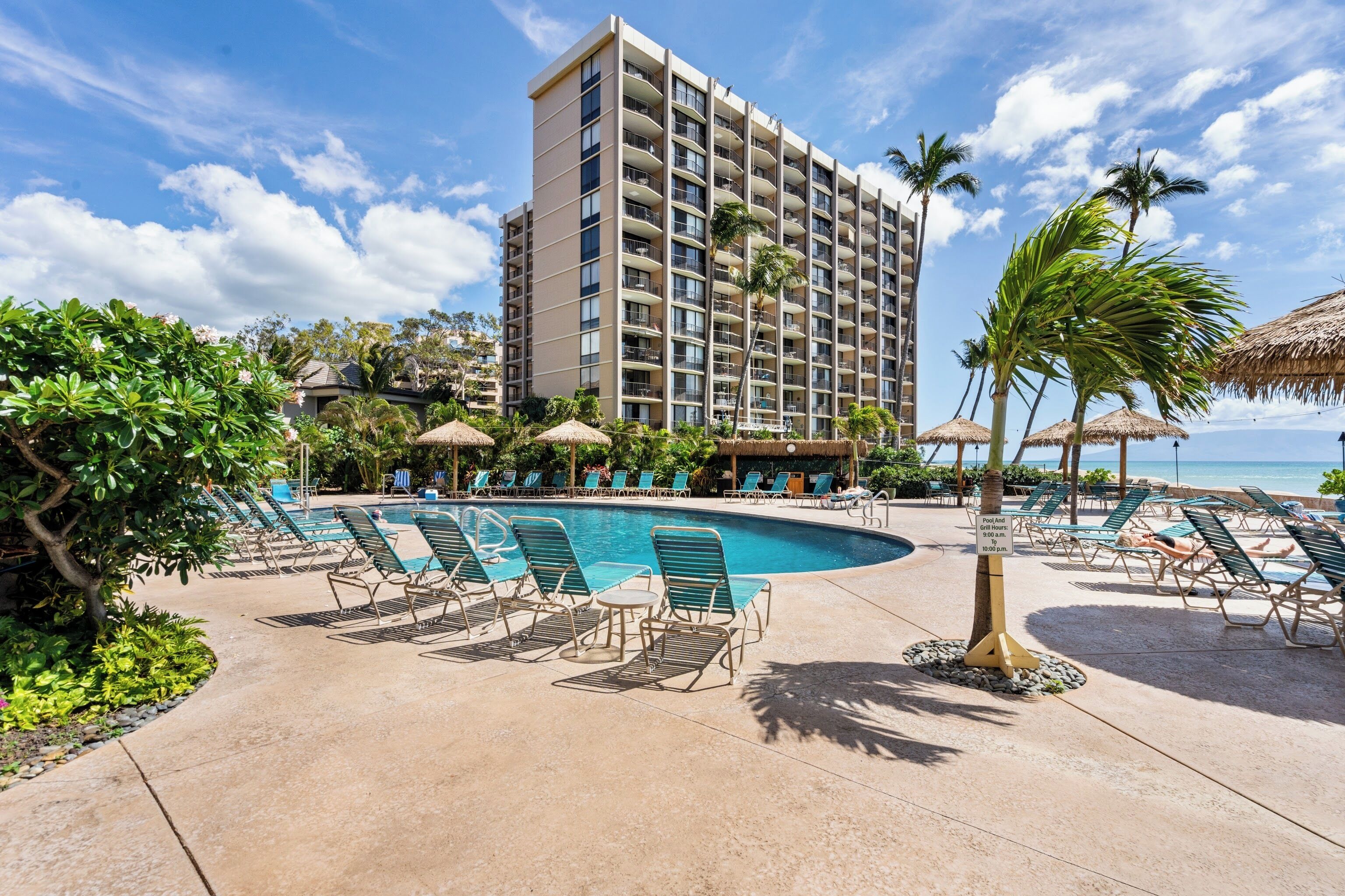 A hotel with a pool area, lounge chairs, and a view of the ocean.