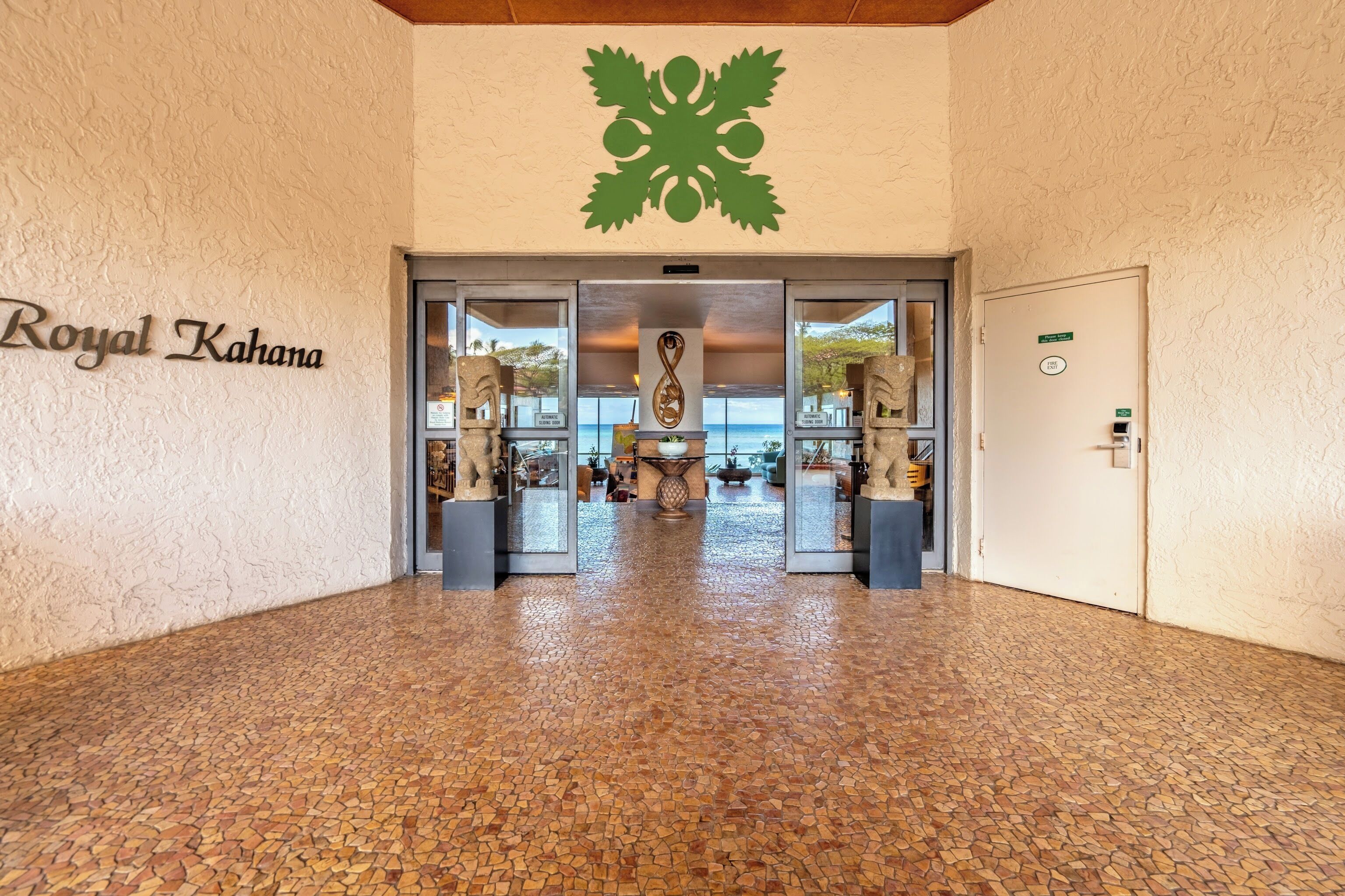 Entrada d'hotel amb un sòl de mosaic, un rètol que diu "Royal Kahana" i un emblema decoratiu sobre les portes.