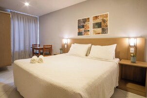 Ein Hotelzimmer mit einem großen Bett, zwei Nachttischen, einem Sessel und zwei Wandlampen.