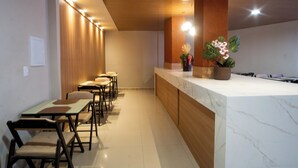 A modern hotel lobby with a marble reception desk, wooden paneling, and a row of bar stools. - Marezzi Hotel (Aracaju)