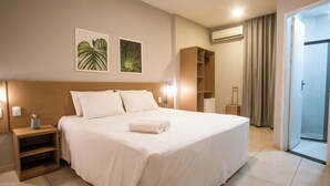 A hotel room with a large bed, a wooden nightstand, a small plant, and a wardrobe. - Marezzi Hotel (Aracaju)