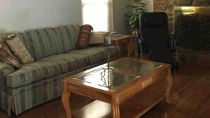 A living room with a wooden coffee table, a sofa, a stone fireplace, and a ceiling fan.