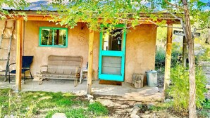 A rustic house with a porch, a bench, and a door. - Writer’s Farm Cabin: Hot Tub Saunas Farm Animals (San Cristobal)