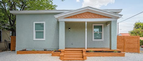 A single-story house with a front porch, a brick gable, and a gravel driveway.