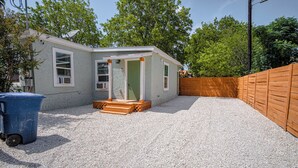 A small, single-story house with a gravel driveway and a wooden fence. - Cozy and Lovely 2BR 1BA Apt#b Near Lively Downtown (San Antonio)