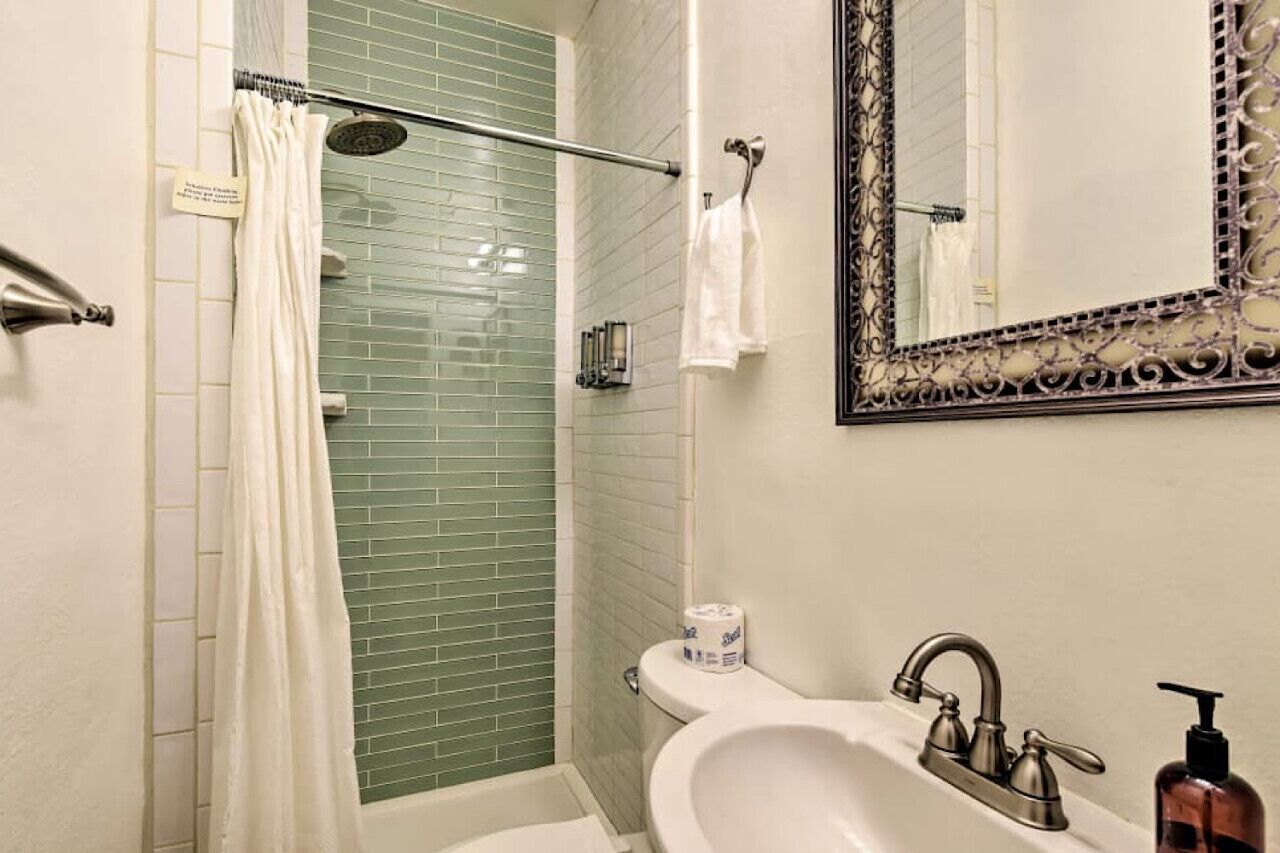 A bathroom with a shower, a sink with a mirror, and a toilet.