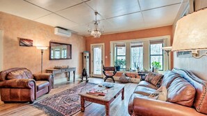 Ein geräumiges Wohnzimmer mit Ledersofas, einem Holztisch und einer Deckenleuchte.