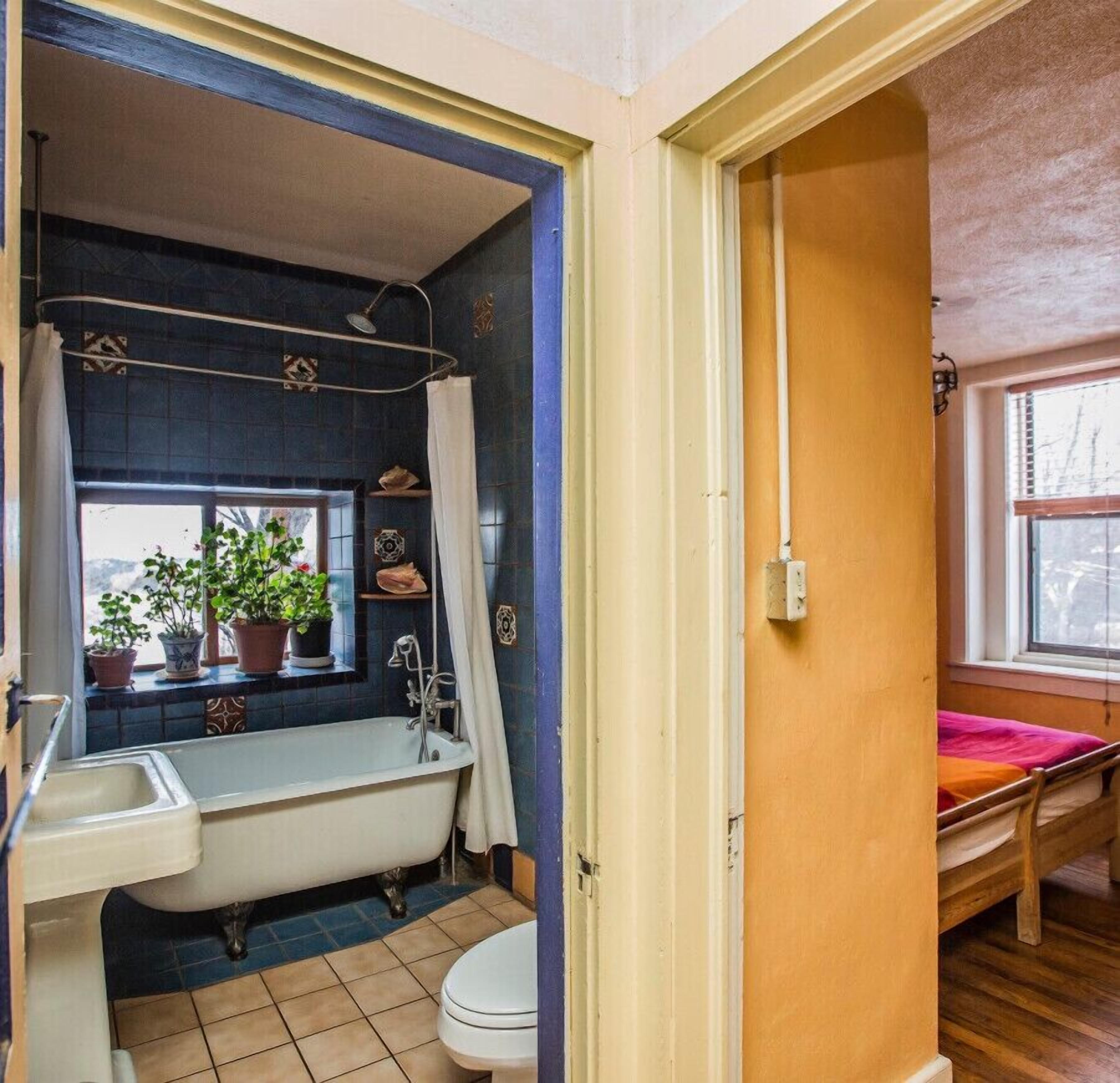A bathroom with a bathtub, sink, toilet, and a window with plants.