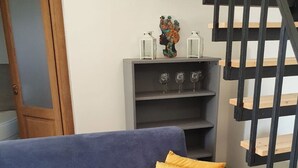 A blue sofa with a yellow pillow in a living room with a grey bookshelf and a black staircase. - Rustic Sicilian hamlet area Partinico / Alcamo/ Balestrate (Partinico)