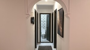 A hallway with a white door at the end, leading to a bathroom with patterned tiles. - My home in Tangier (Tanger)