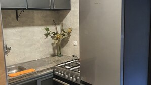 A kitchen with a stainless steel refrigerator, a gas stove, a sink, and cabinets. - My home in Tangier (Tanger)