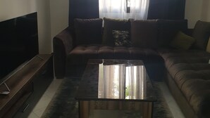 A living room with a sofa, a coffee table, a TV, and a window with curtains. - My home in Tangier (Tanger)
