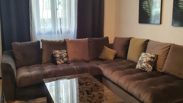 A living room with a sectional sofa, a glass coffee table, and a rug. - My home in Tangier (Tanger)