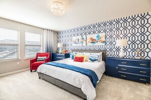 Un dormitorio con una cama, una silla roja, un aparador y una pared con diseño.