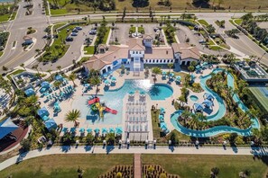 Vista aérea de un resort con piscina central, diversas zonas de natación y un paisaje cuidado.