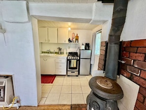 A compact kitchen with white cabinets, a gas stove, a small oven, and a brick wall stove. - GEORGIA O'KEEFE (San Cristobal)
