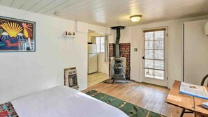 Una habitación con una cama, una mesa, una chimenea y una puerta con un ventanal.