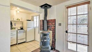 Una cocina con estufa, refrigerador y estufa de leña.