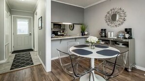 Une cuisine compacte avec un coin repas, comprenant une table ronde avec des chaises, une machine à café et un miroir décoratif au mur.