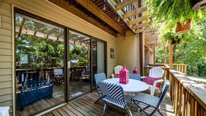 Une terrasse couverte avec une plateforme en bois, des sièges d’extérieur et une vue sur la végétation environnante.