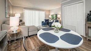 Un salon moderne avec une table ronde, un canapé et un téléviseur en arrière-plan.