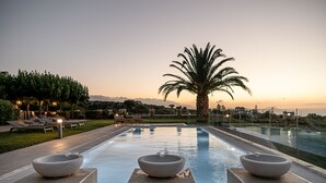 A poolside area with lounge chairs, a palm tree, and a large bowl on a platform. - Villa Heora - The Floating Residence (Tria Monastiria)