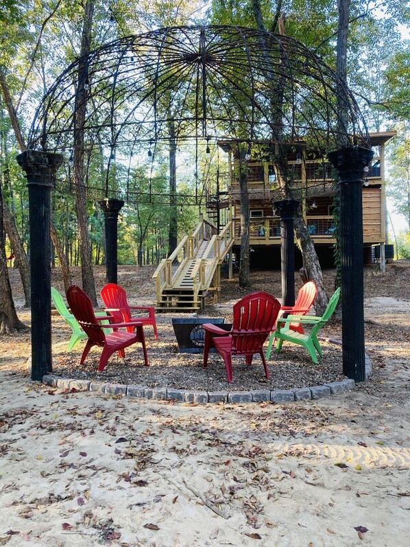 A wooden deck with Adirondack chairs and a fire pit.