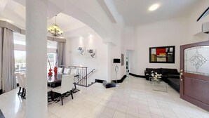 Un vaste salon comprenant un coin repas, un escalier et un lustre moderne.