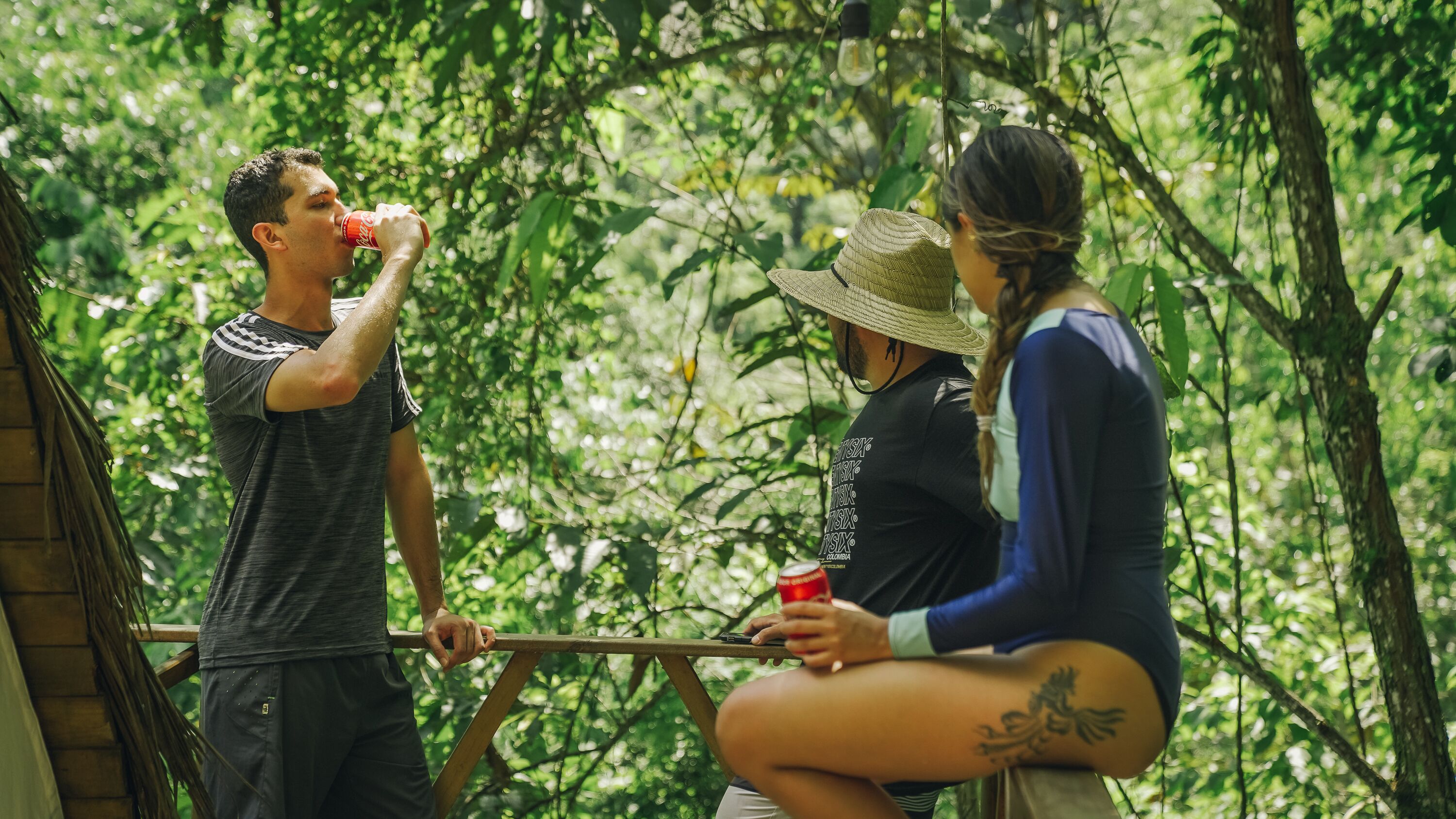 Three people sitting on a wooden bench in a lush, green outdoor setting.