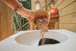 A hand pouring a brown granular substance into a white sink.