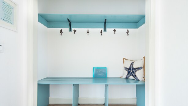 Une pièce avec un bureau de couleur turquoise, une décoration en forme d’étoile de mer et un panneau d’accueil encadré.