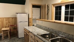 Una cocina compacta con refrigerador, pileta doble, armarios de madera y ventana.